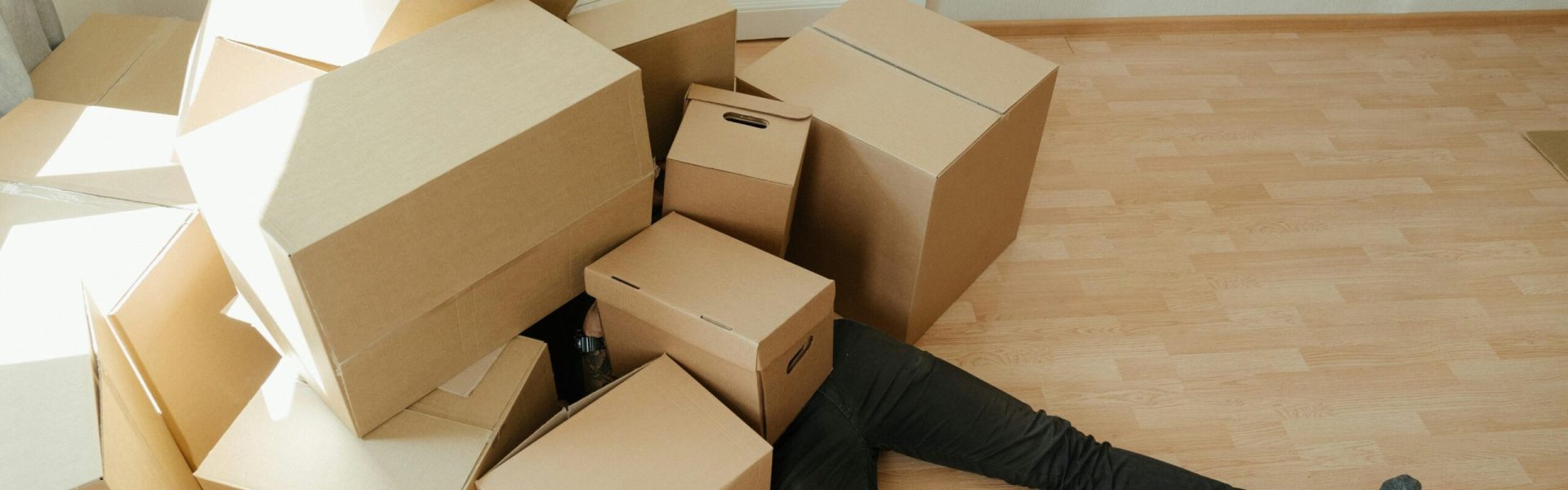 pexels-photo-4553182-4553182 A person overwhelmed by cardboard boxes during a home move, symbolizing stress and relocation.